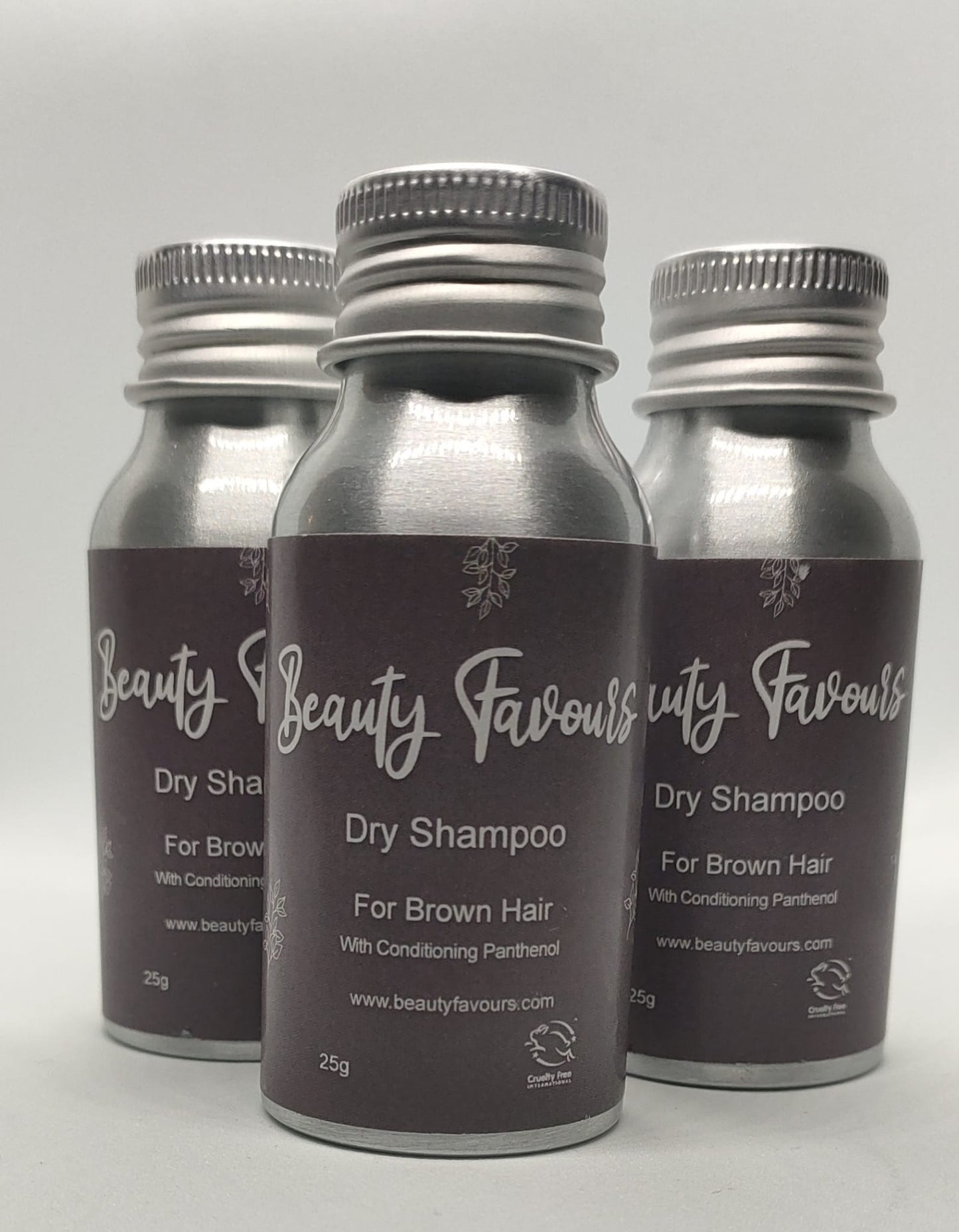 Three bottles of Beauty Favours dry shampoo for brown hair on a light gray background