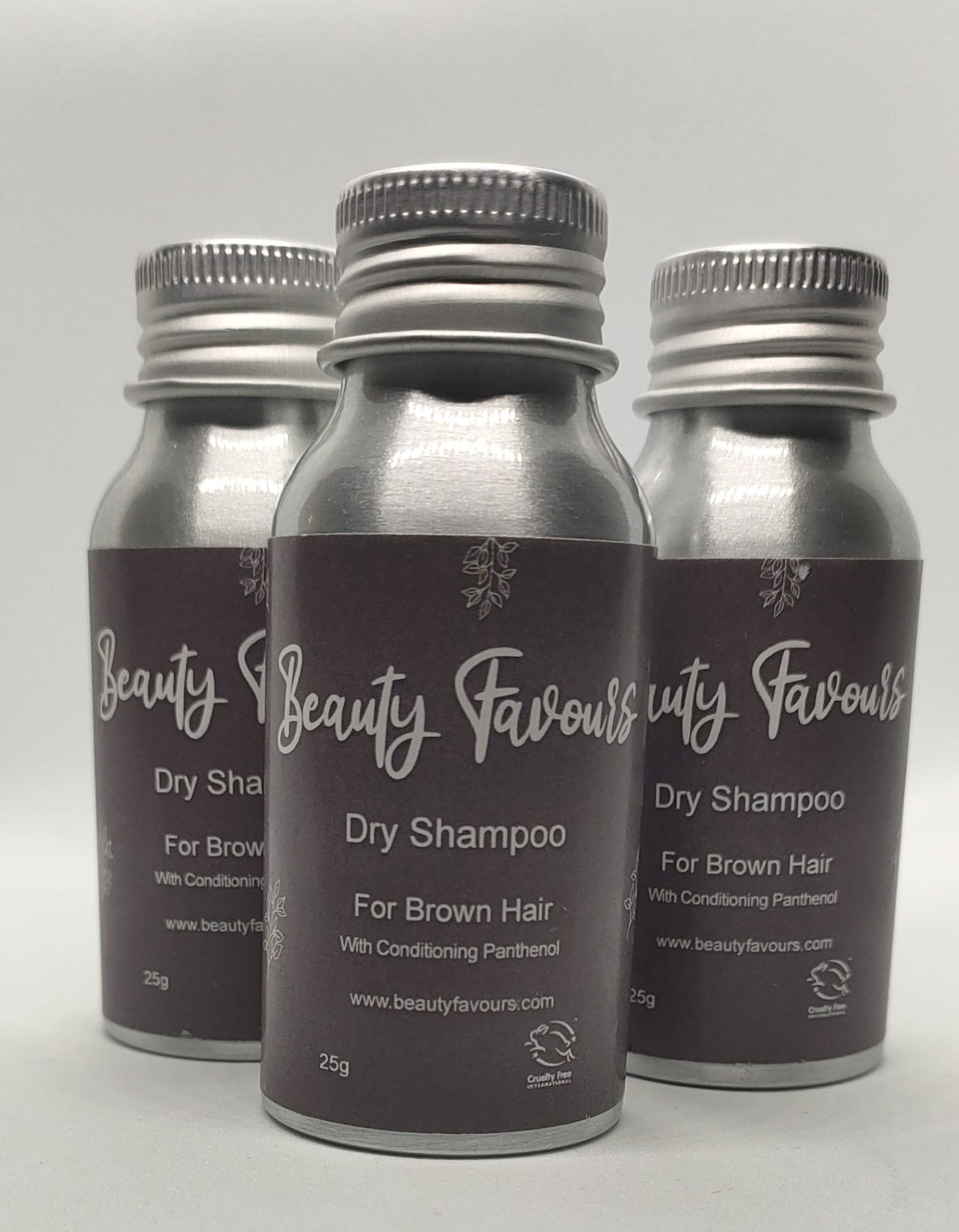 Three bottles of Beauty Favours dry shampoo for brown hair on a light gray background